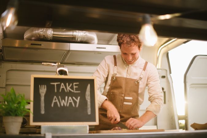 Happy cook cutting ingredients in food truck