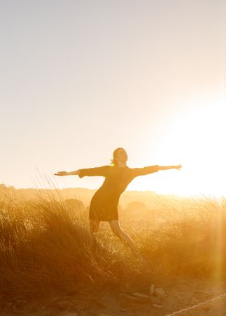 Woman posing between field at sunset