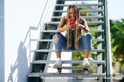 Female skater texting on phone on stairs, copy space 5RlMrb