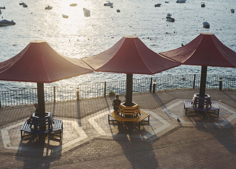 Benches lining the embankment of sea with anchored yachts