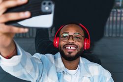 Cheerful Black man in headphones taking selfie