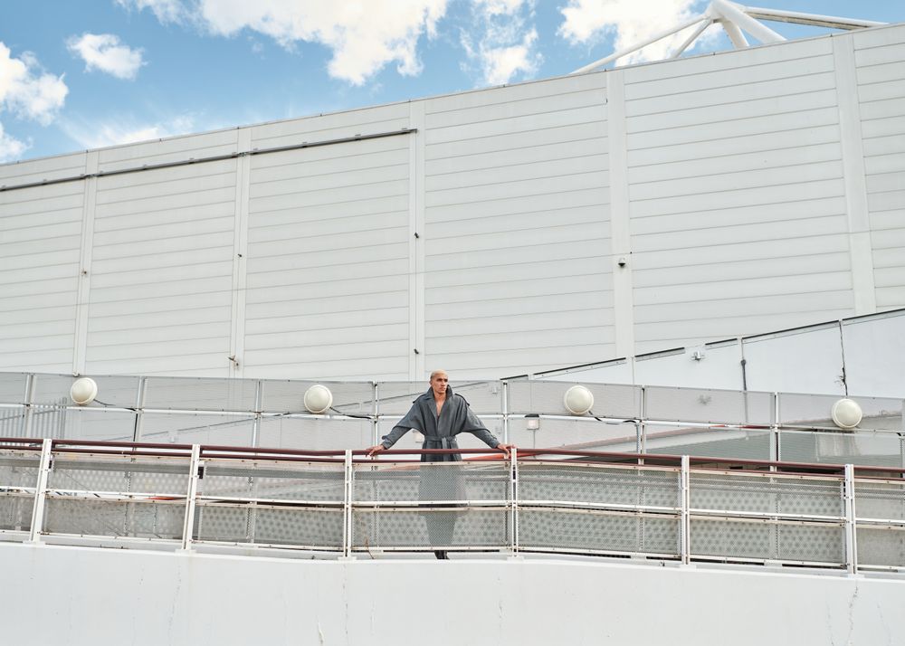 Stylish young man leaning on fence on ramp
