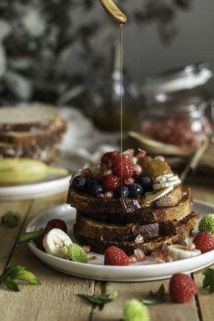 Honey pouring over fried toasts with fruit