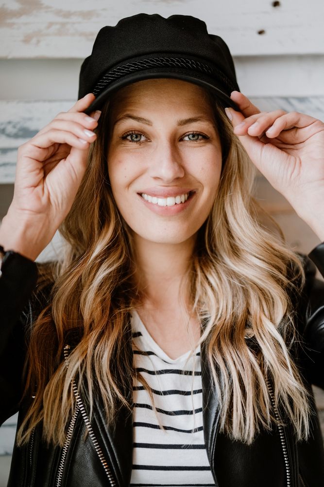 Woman thoughtfully looking at camera touching cap