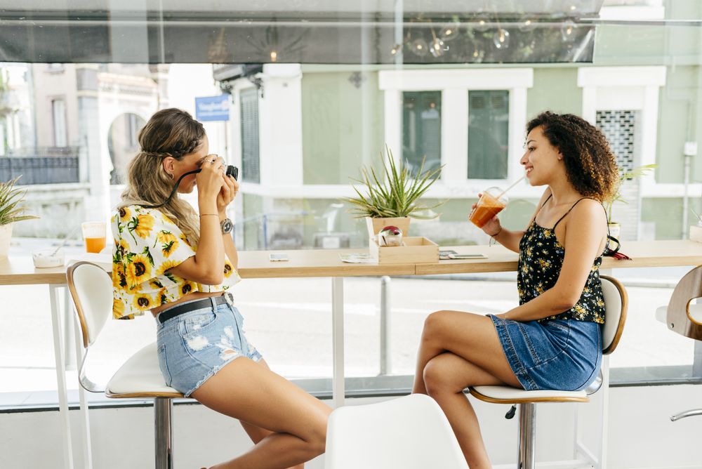 Woman taking photo of friend in cafe