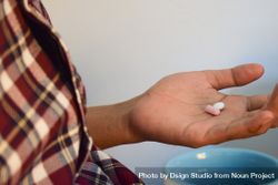 Side view of person with two pills in palm of hand 4mWRaX
