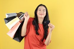 Indonesian Young Woman Holding Lots of Shopping Bag on Right Hand and Credit card on Left Hand