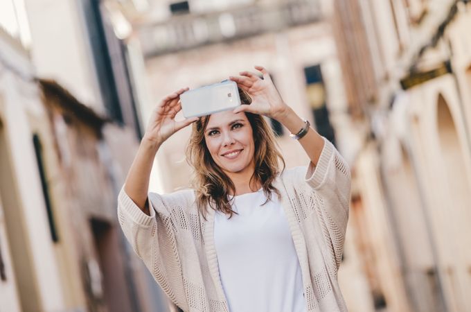 Smiling woman taking selfie in city