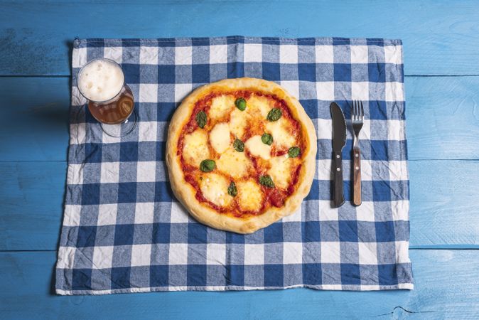 Mozzarella pizza, basil and beer on blue table