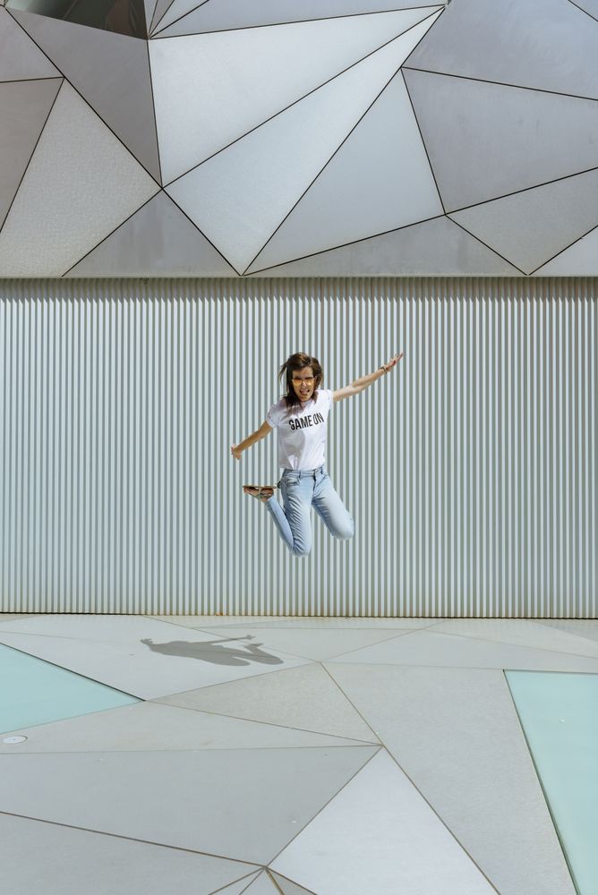 Cheerful woman jumping near modern wall