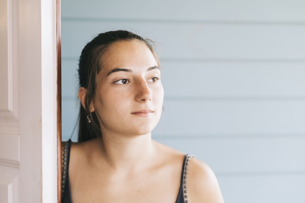 Portrait of a calm young woman in summer dress by door
