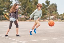 Content teen boy and girl playing basketball in city