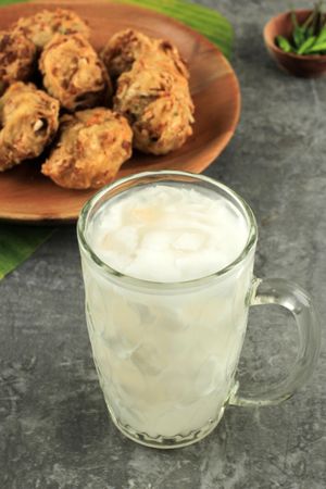 Icy coconut summer drink with plate of fried snacks