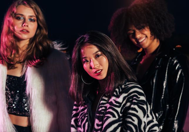 Group of women in stylish clothes posing at night