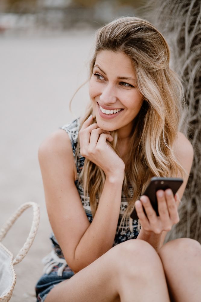 female using smartphone on beach