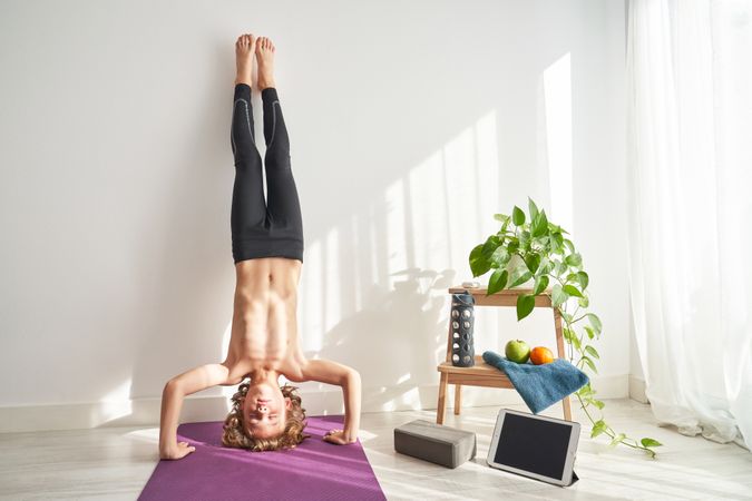 Shirtless child closing eyes in headstand in light room