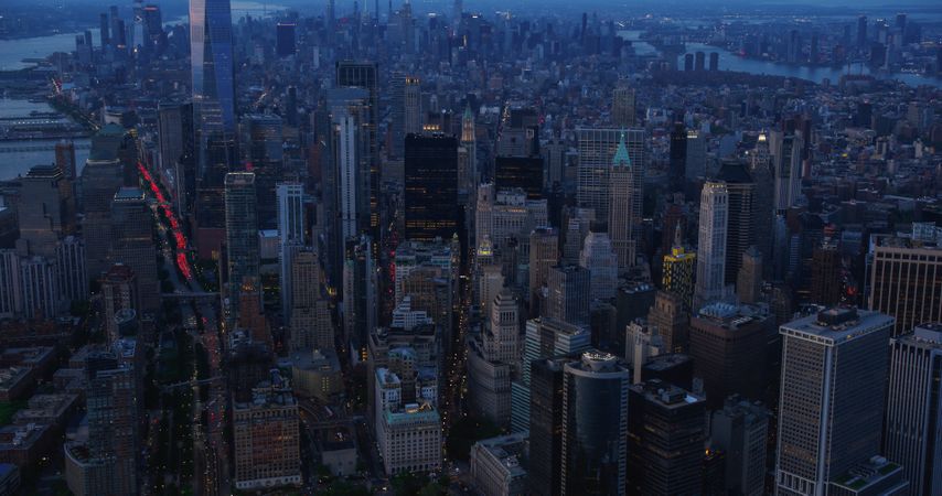 Wall Street Office Buildings at Night: Scenic Aerial New York City View of Lower Manhattan Architecture. Panoramic Financial District Image from a Helicopter. Evening Cityscape with Skyscrapers