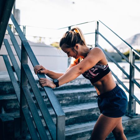Young woman stretching on stadium stairs