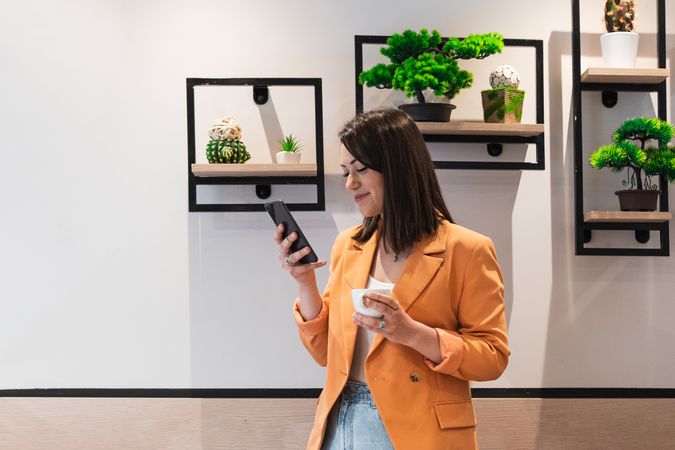 Delighted woman browsing smartphone in office