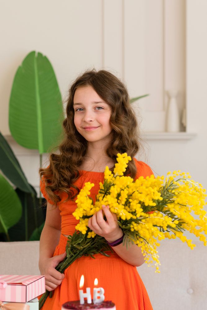 Girl in an orange dress holding yellow flowers
