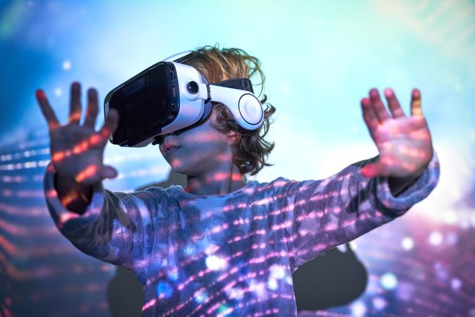Cute child with arms stretched forward exploring cyberspace in VR Headset