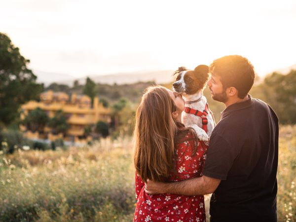 Happy couple with friendly cute dog outdoors