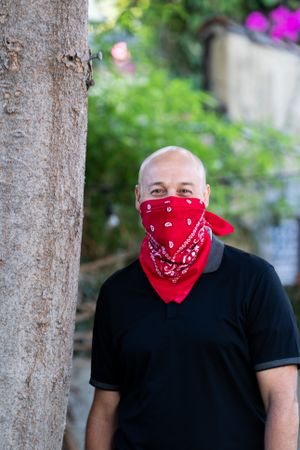 Man with red bandana outside by tree