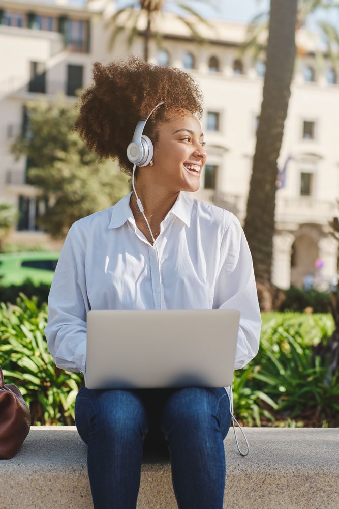 Smiling Black woman working on netbook on street