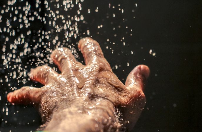 Close-up shot of left human hand with water drops