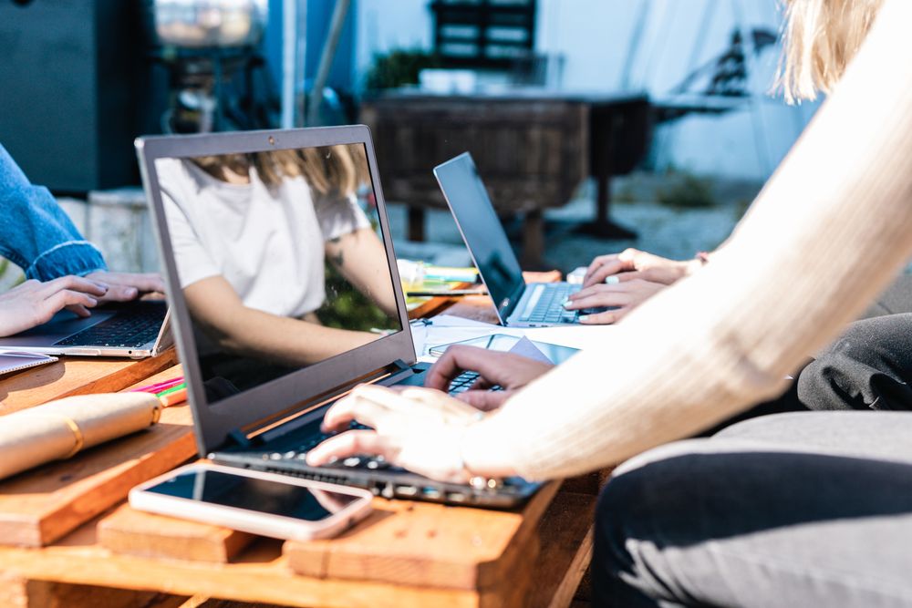 Detail of hands working with computers,notes and mobile phones on a wooden table.Business and study.