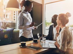 Black woman standing and leading a business meeting