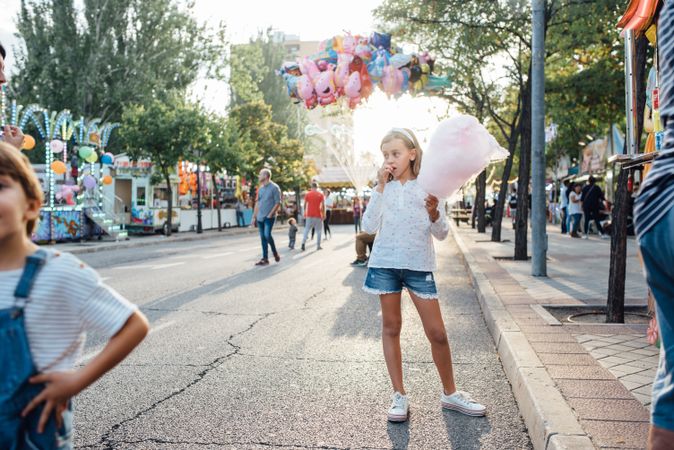 Cheerful girl eating cotton candy on street