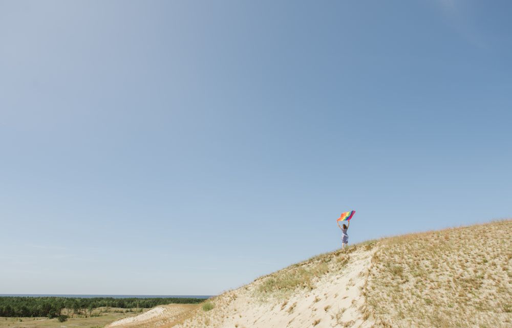 Young woman with rainbow banner against sky
