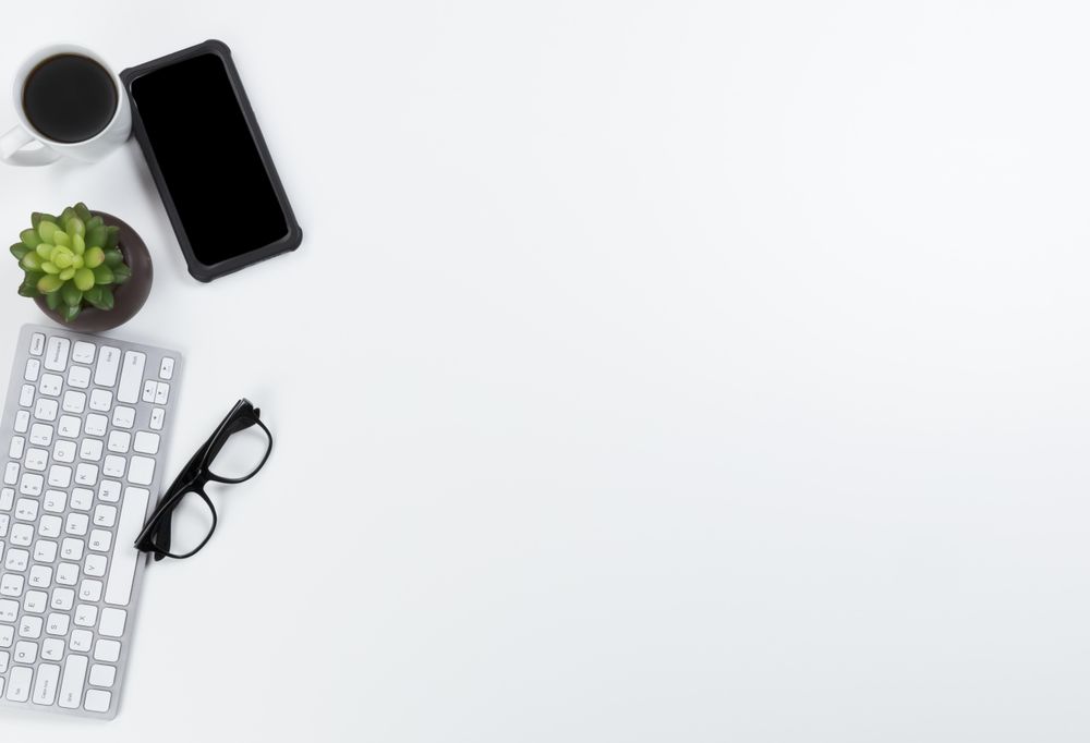 Keyboard, smartphone, and coffee on left side of desktop