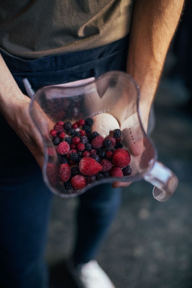 Man holding blender full of berry mix for smoothie