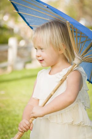 Cute Baby Girl Holding Parasol Outside At Park