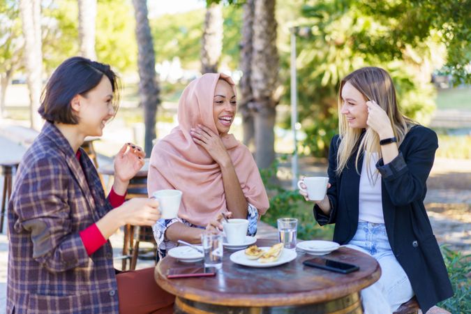 Three women enjoying coffee and baked goods on a beautiful sunny day