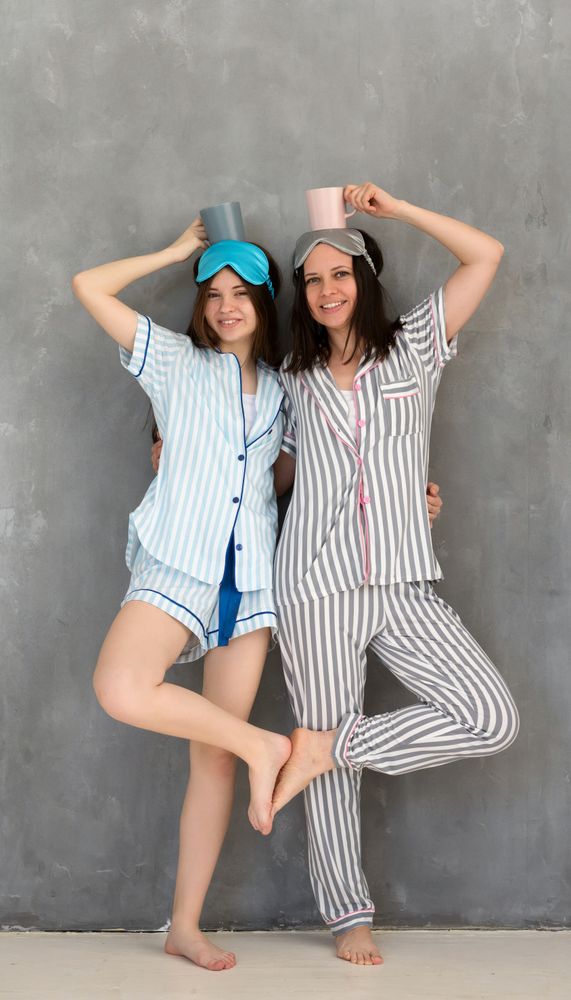 Mother and daughter balancing cups on heads in pajamas.