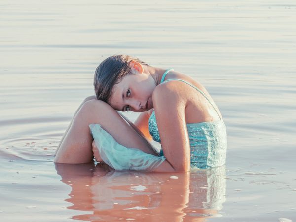 Teenage girl sitting in fresh water in sunny day