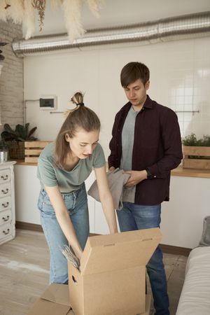Cheerful couple unpacking boxes in light kitchen