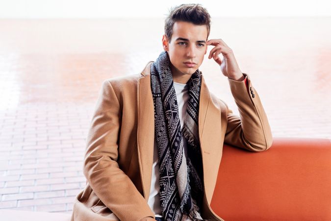 Young man in coat, scarf, blue jeans and in autumn jacket