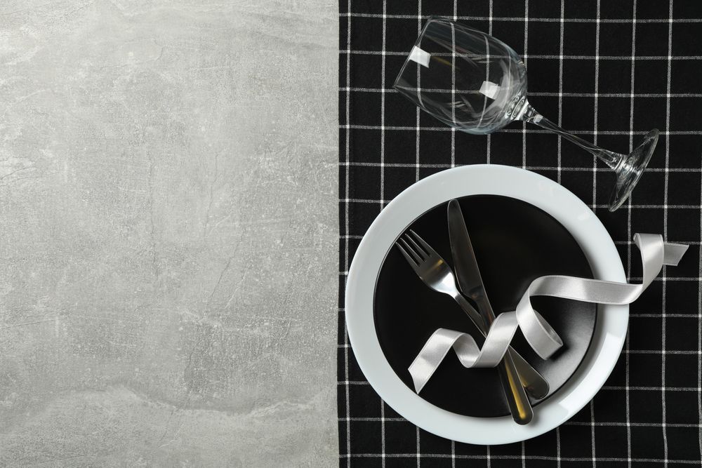Table setting with napkin, cutlery and wine glass on gray background