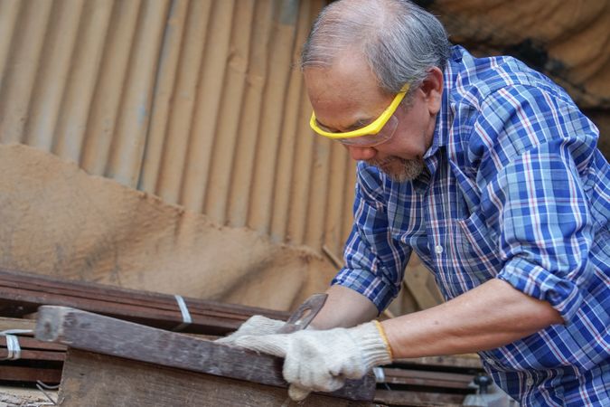 Asian carpenter working on a wooden plank in the shop