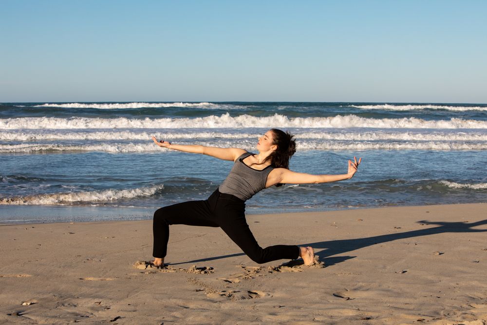 Young woman dancing and posing near water on shore