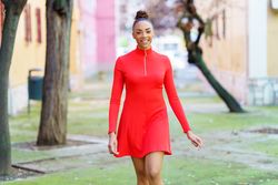 Smiling female in casual red dress strolling outside