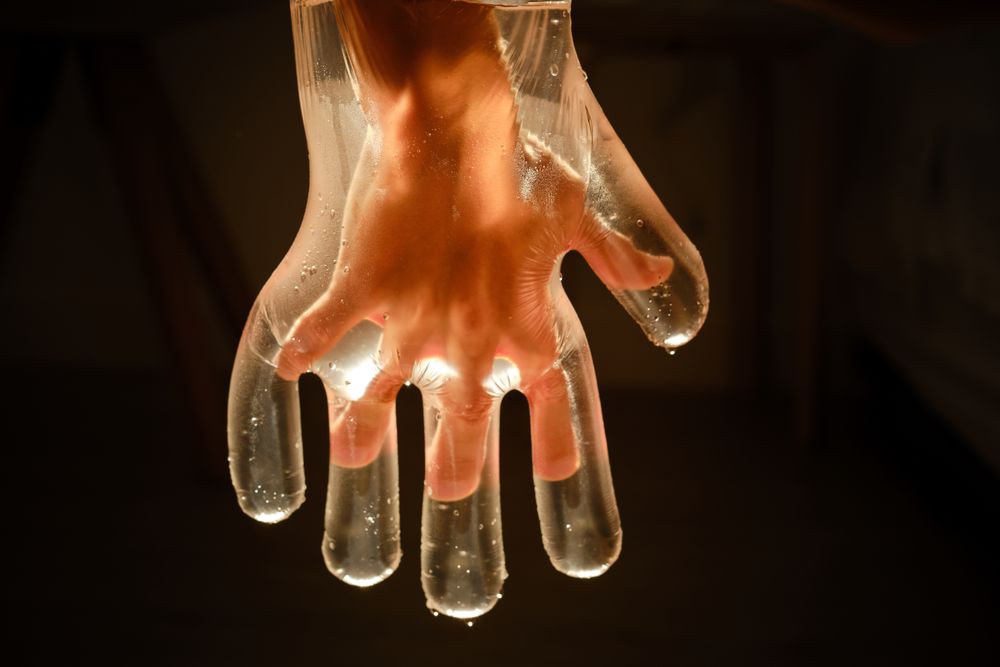 Crop child in plastic glove with water