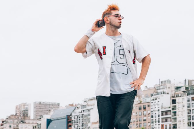 Contemporary male in casual trendy wear calling on smartphone