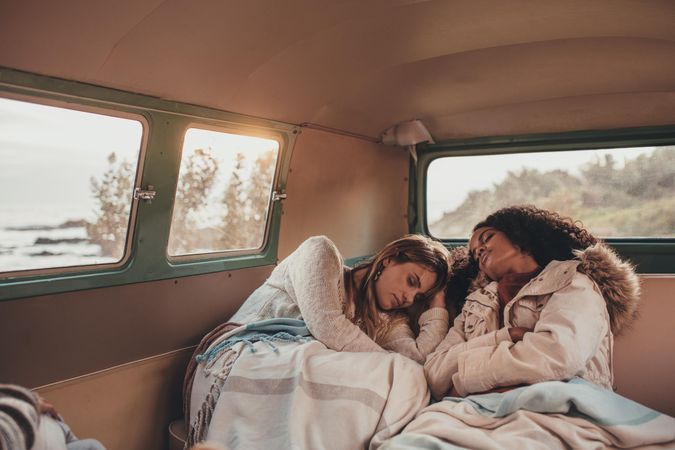 Two women friends on road trip sleeping inside the van
