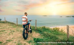 Male standing with bicycle looking down at beautiful ocean view 4Z2lA4