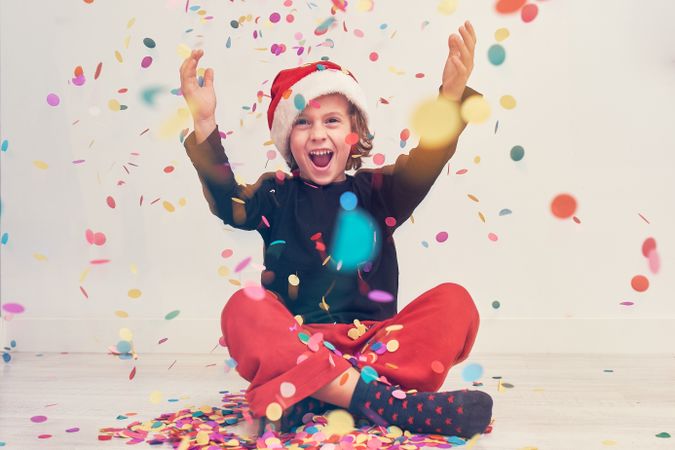 Happy boy in Santa hat under confetti